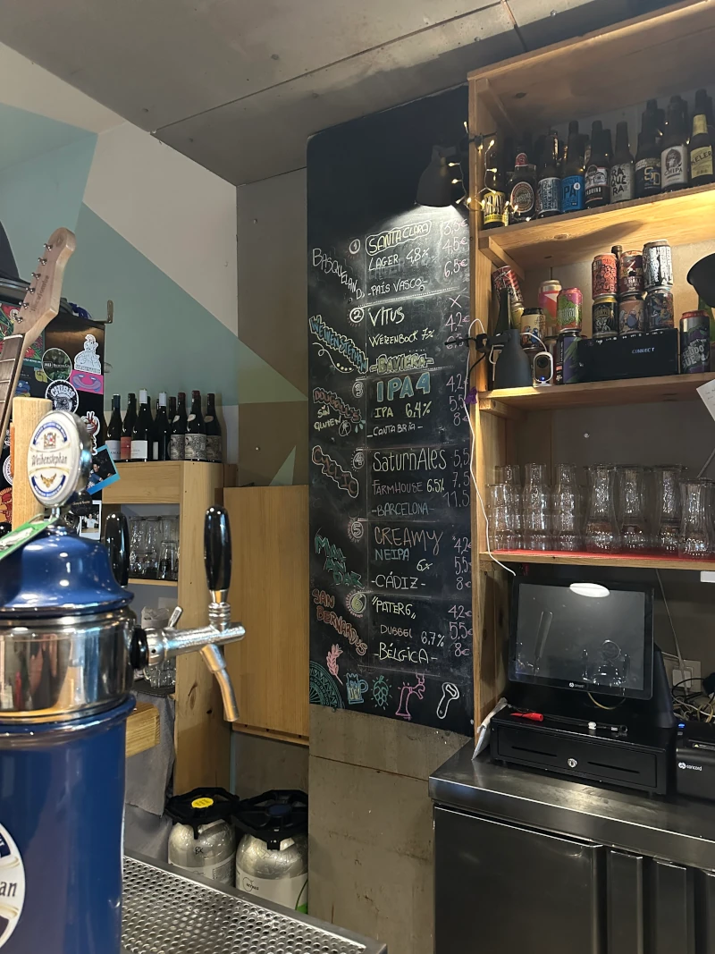 Tap list chalkboard and bottle shelf at La Linterna Ciega Sevilla